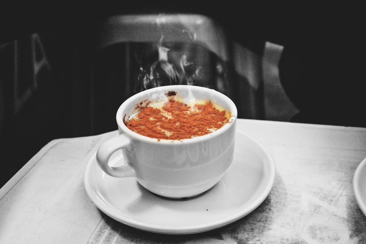 A steaming cappuccino with cinnamon, captured in a cozy indoor cafe setting.